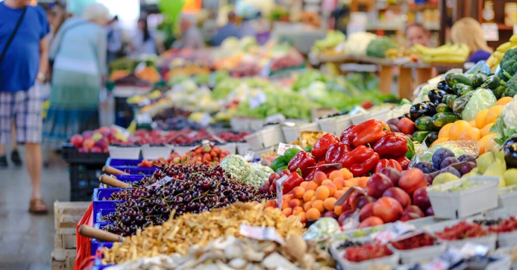 Colorful assortment of fresh fruits and vegetables in a bustling outdoor market scene.